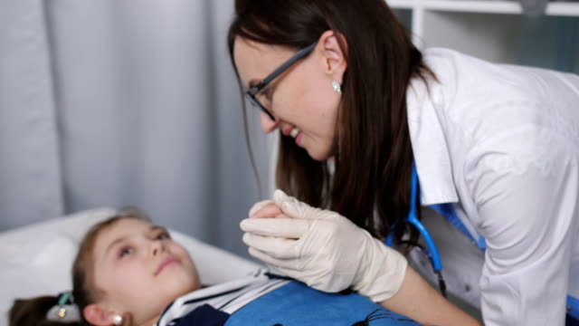 Lächelt-freundlich-Ärztin-im-Gespräch-mit-kleinen-Patienten-liegen-auf-einem-Krankenhausbett-in-der-Kinderarztpraxis
