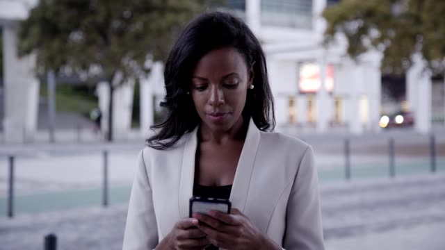 Ernst-afroamerikanische-Frau-mit-Smartphone-in-Stadt