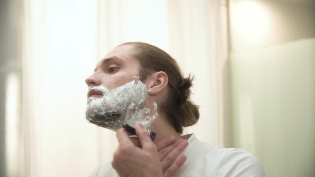 Hombre-afeitado-barba-con-navaja-en-baño