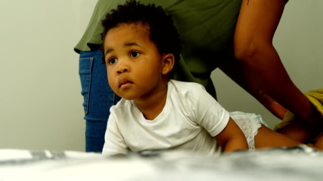 Sección-media-de-la-joven-madre-negra-ayudando-a-su-hijo-a-cambiarse-la-ropa-en-la-cama-en-casa-cómoda-4k