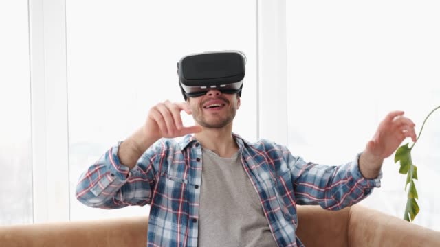 Man-playing-game-with-virtual-reality-goggles-at-home