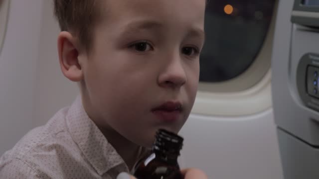 Kid-in-plane-taking-medicine