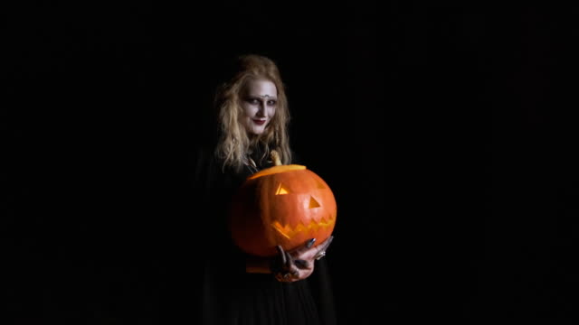 Imagen-de-Halloween-.-La-joven-bruja-con-ropa-negra-sostiene-calabaza-en-sus-manos.