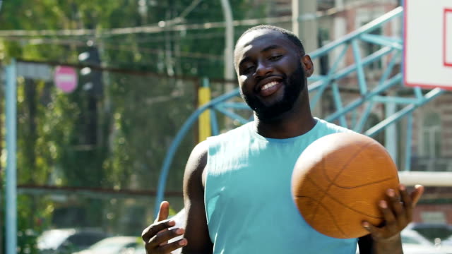 Happy-man-throwing-ball-from-one-hand-to-another,-proud-of-streetball-victory