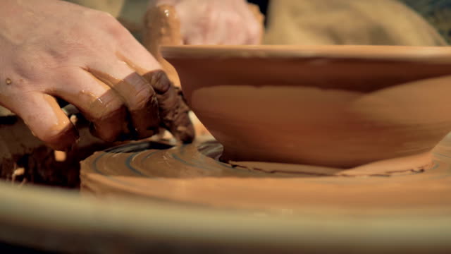 A-detailed-view-on-potters-hands-cutting-away-excess-clay-from-a-bowl.