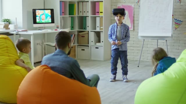 Kleiner-Junge-in-VR-Kopfhörer-rezitieren-eine-Lektion-in-der-Grundschule