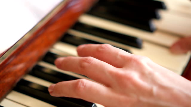 Weibliche-Finger-Tasten-auf-Retro-Klavier-Tastatur-zu-spielen.-Geringe-Schärfentiefe.-Hände-im-Fokus
