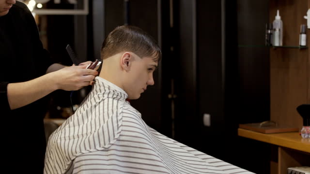 Friseur-schneidet-Kerls-Haare-mit-elektrischen-Rasierapparat-im-barbershop