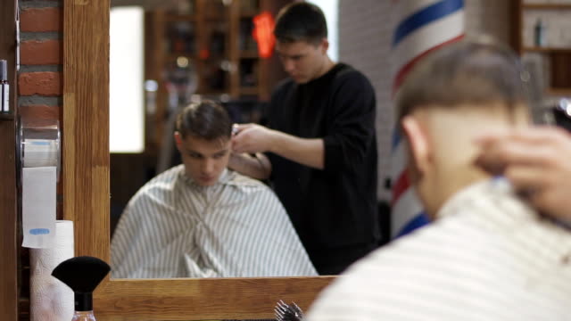 Professional-barber-cuts-hair-with-electric-razor-to-a-young-guy