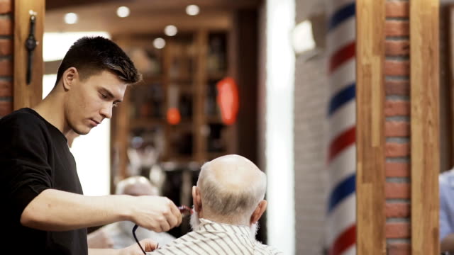 Friseur-rasiert-graues-Haar-von-reifer-Mann-im-barbershop