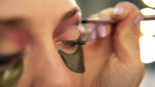 Make-up-artist-applying-eye-shadow-to-model's-eye.-Close-up-view.-Patches