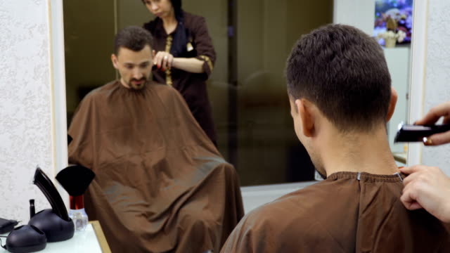 Hairdresser-cuts-hair-of-man-with-electric-razor