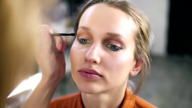 Overview-of-a-make-up-process.-Professional-make-up-artist-gently-putting-nude-eyeshadows-on-an-eyelid.-Attractive-young-blonde-model