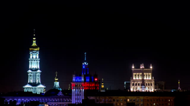 The-bell-tower-of-the-Assumption-Cathedral-Uspenskiy-Sobor,-City-council-and-house-with-a-spire-night-timelapse-in-Kharkiv,-Ukraine