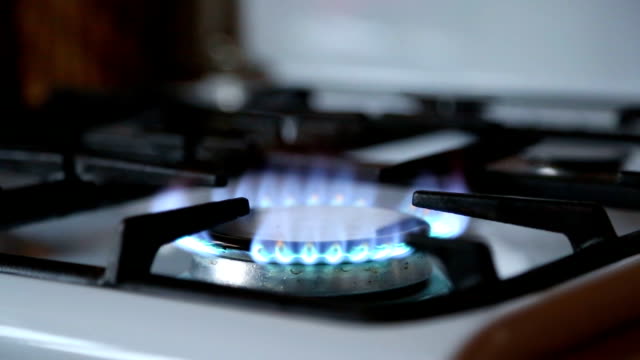 Stove-top-burner-igniting-into-a-blue-cooking-flame