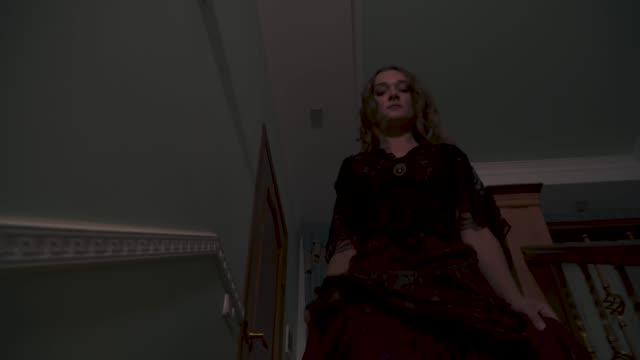 Halloween.-Beautiful-girl-in-a-black-dress-coming-down-the-stairs-in-the-house