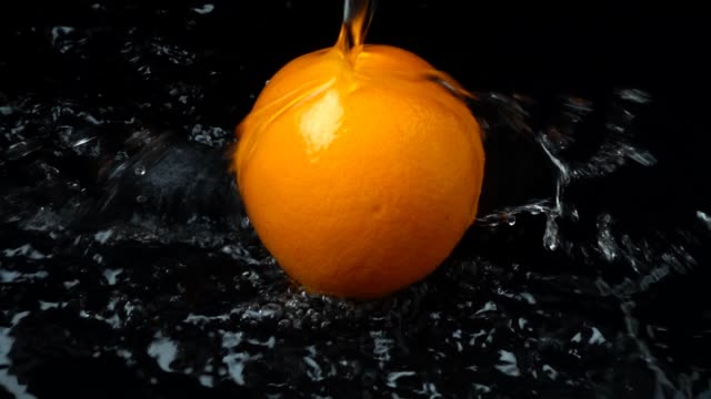 The-stream-of-water-flows-on-orange.-Slow-motion.