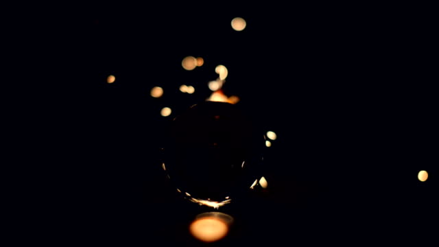Burning-sparkler-behind-a-glass-ball-on-a-black-background.