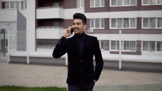Junge-hübsche-Geschäftsmann-Wandern-und-telefonieren-mit-Handy-in-der-Stadt