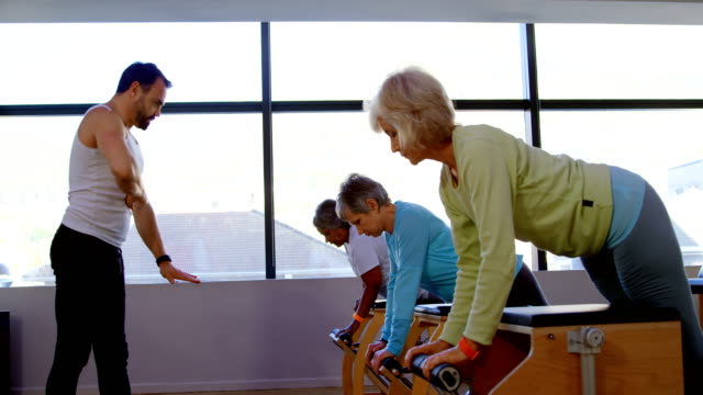 Trainer-assisting-senior-women-to-exercise-4k