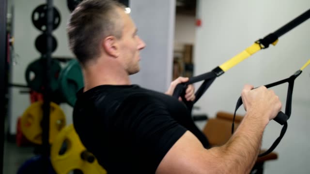 Handsome-man-is-engaged-on-TRX.-Makes-an-exercise-for-the-arms-and-back-4K-Slow-Mo