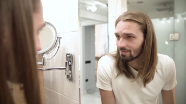 Bathroom.-Man-Looking-In-Mirror-And-Touching-Face