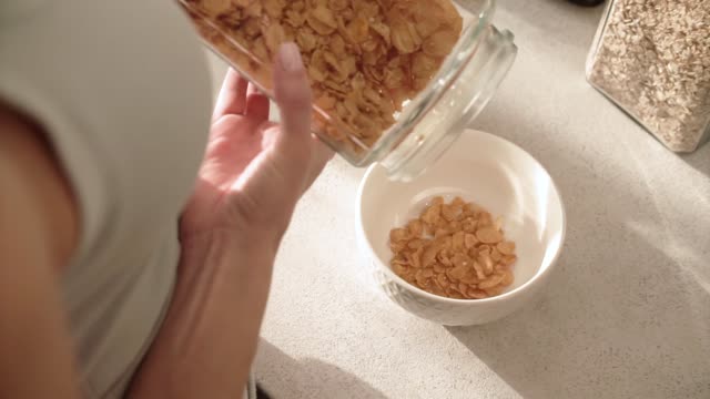 Healthy-Breakfast.-Woman-Hands-Filling-Bowl-By-Cereals-Muesli