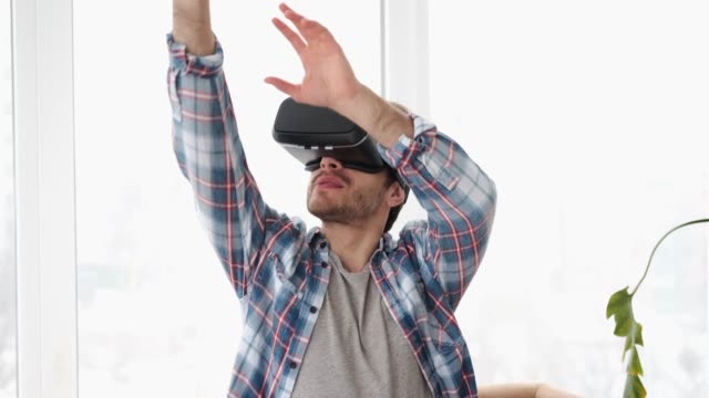 Man-wearing-vr-headset-and-gesturing-on-sofa