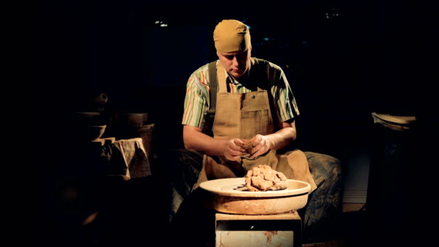 A-potter-in-a-dark-room-kneads-clay.