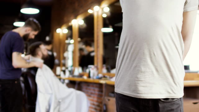 Friseur-macht-Frisur-für-jungen-Mann-bei-unscharfen-Hintergrund-des-Pinsels