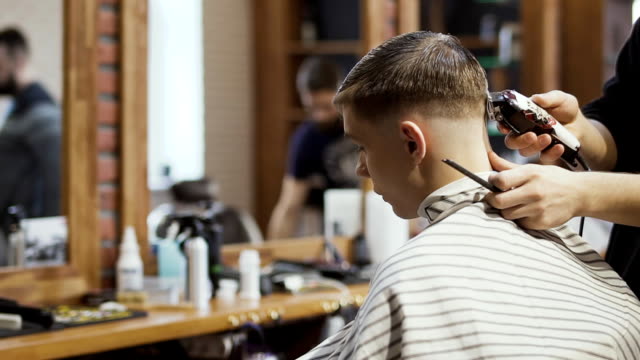 Stylistin-macht-moderne-Frisur-für-jungen-Kerl-im-barbershop