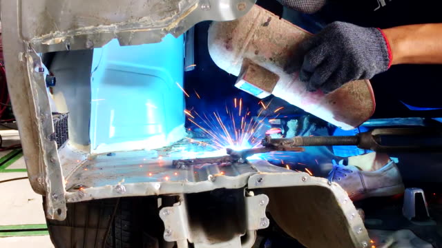 Soldar-acero-con-electricidad-en-taller-de-reparación-de-cuerpo-de-auto,-closeup