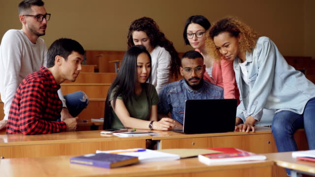 Grupo-de-estudiantes-está-utilizando-laptop-sentado-en-clase-y-hablar,-los-jóvenes-está-trabajando-en-el-proyecto.-Estilo-de-vida-moderno-concepto-de-tecnología-y-educación-superior.