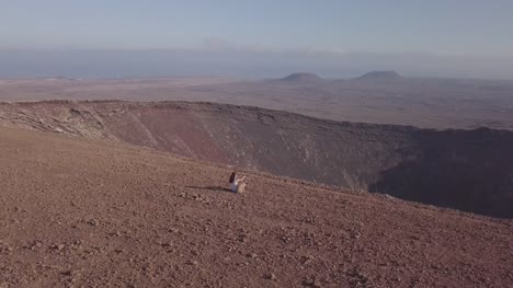 girl-with-her-dog-on-the-top-of-the-volcano,-fuerteventura