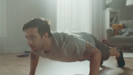 Slow-Motion-Close-Up-of-a-Strong-Athletic-Fit-Man-in-T-shirt-and-Shorts-Doing-Clapping-Push-Up-Exercises-at-Home-in-His-Spacious-and-Bright-Living-Room-with-Minimalistic-Interior.