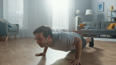 Muscular-Athletic-Fit-Man-in-T-shirt-and-Shorts-is-Doing-Push-Up-Exercises-at-Home-in-His-Spacious-and-Bright-Apartment-with-Minimalistic-Interior.