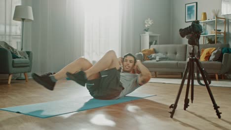 Strong-Athletic-Fit-Man-in-T-shirt-and-Shorts-is-Recording-his-Crisscross-Crunch-Workout-on-Camera-for-His-Blog.-Scene-takes-place-in-His-Spacious-and-Bright-Living-Room-with-Minimalistic-Interior.