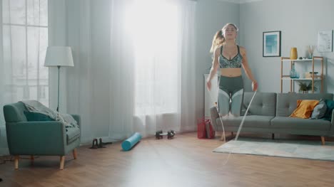 Strong-and-Fit-Beautiful-Girl-in-an-Athletic-Top-Energetically-Exercises-With-Jump/Skipping-Rope-in-Her-Bright-and-Spacious-Living-Room-with-Minimalistic-Interior.