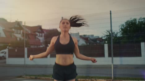 Beautiful-Energetic-Fitness-Girl-Skipping/Jumping-Rope.-She-is-Doing-a-Workout-in-a-Fenced-Outdoor-Basketball-Court.-Afternoon-Footage-After-Rain.