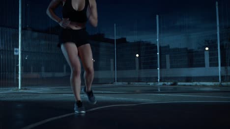 Close-Up-of-a-Beautiful-Energetic-Fitness-Girl-Doing-Footwork-Running-Drill.-She-is-Doing-a-Workout-in-a-Fenced-Outdoor-Basketball-Court.-Night-Footage-After-Rain-in-a-Residential-Neighborhood-Area.