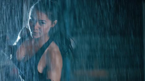 Beautiful-Sporty-Fitness-Girl-is-Doing-Sharowboxing-Exercises.-She-is-Doing-a-Workout-at-Night-in-Heavy-Rain-with-One-Light-Behind-Her.