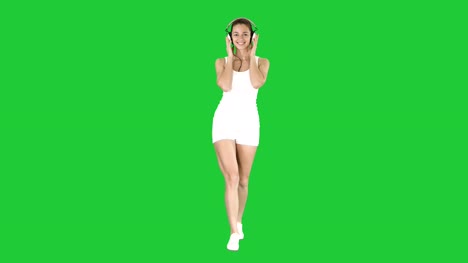Sportswoman-listening-music-in-headphones-on-a-Green-Screen,-Chroma-Key