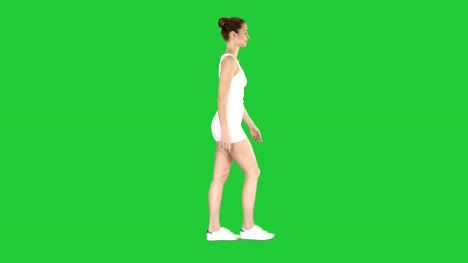 Mujer-joven-en-ropa-de-deporte-pasear-mirando-hacia-abajo-en-una-pantalla-verde-Chroma-Key