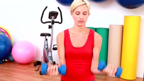 Rubia-mujer-levantamiento-pesas-en-pelota-de-ejercicio