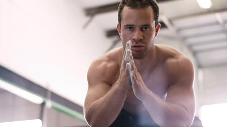A-fit-young-man-chalking-up-at-the-gym-and-staring-into-the-camera