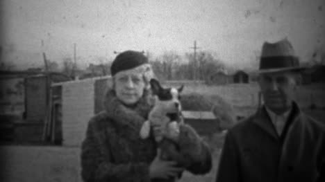 1933:-pareja-mostrando-nuevo-perro-pequeño-en-la-ropa-de-invierno-formal.