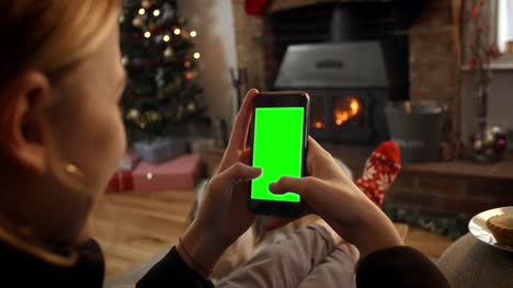 Mujer-en-línea-con-el-teléfono-móvil-en-habitación-listo-para-Navidad