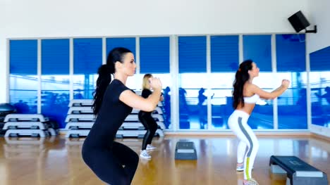 Tres-atractivas-mujeres-entrenando-las-nalgas-y-las-piernas-en-el-gimnasio-delante-del-espejo