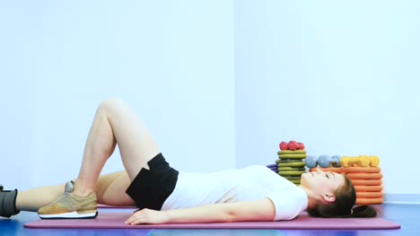 Chica-linda-entrenando-su-pierna-con-peso-en-el-centro-de-rehabilitación