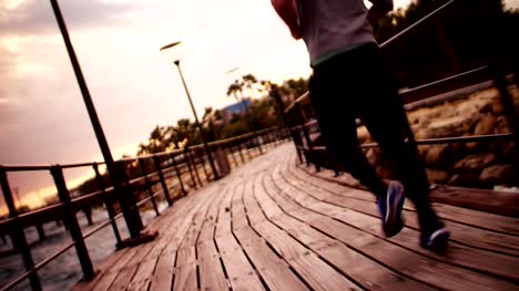 Junger-sportlicher-Mann-läuft-direkt-am-Meer-bei-Sonnenuntergang
